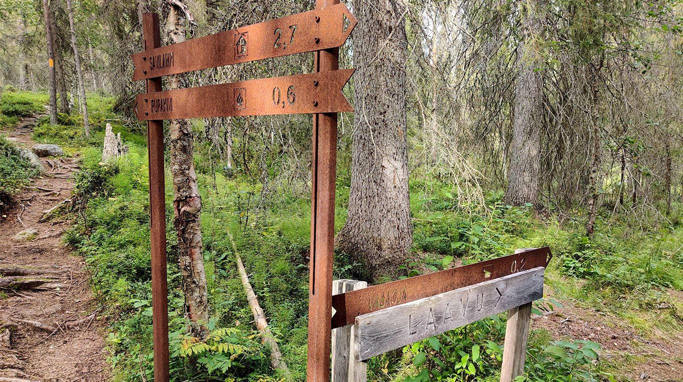 A photo of the somewhat messy signpost, showing directions to the lean-to and the next locations in Karhunkierros.