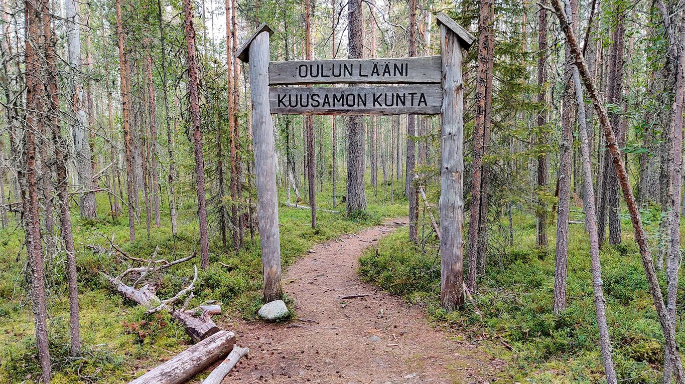 A wooden sign, between two wooden posts indicating that you are now in Oulu province, and entering Kuusamo municipality.
